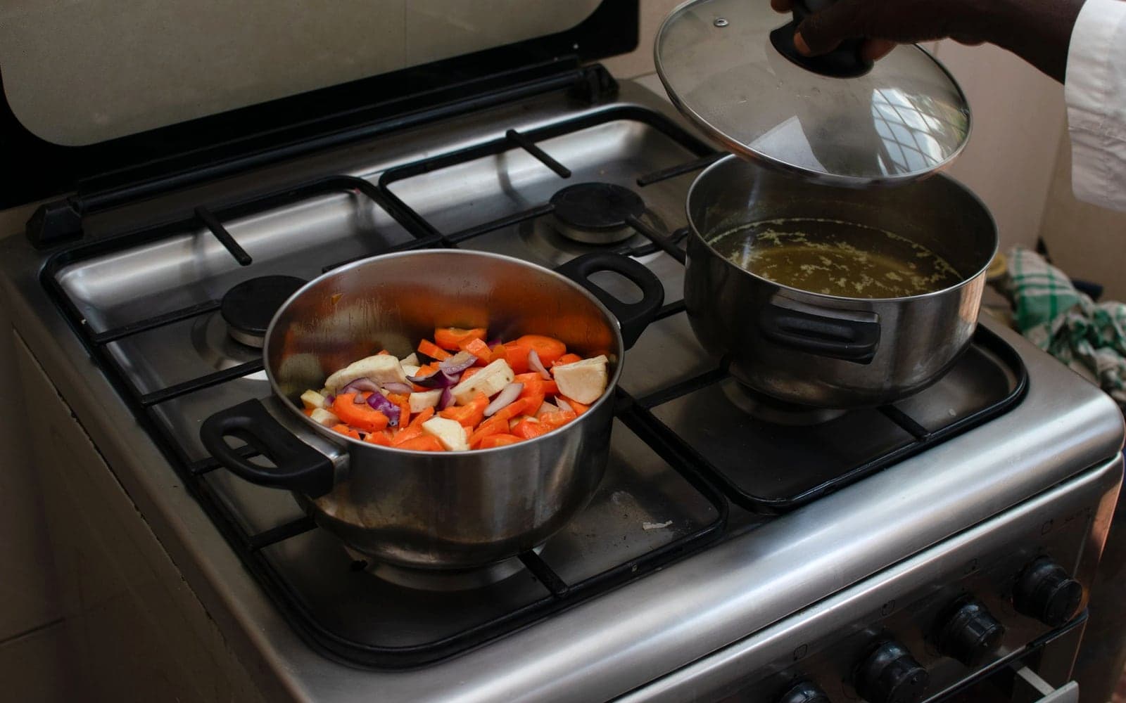 Panelas ao lume num fogão com legumes e caldo a cozinhar